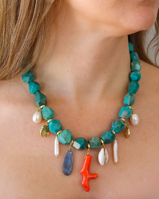 Turquoise and coral beaded necklace with hanging charms worn around the neck