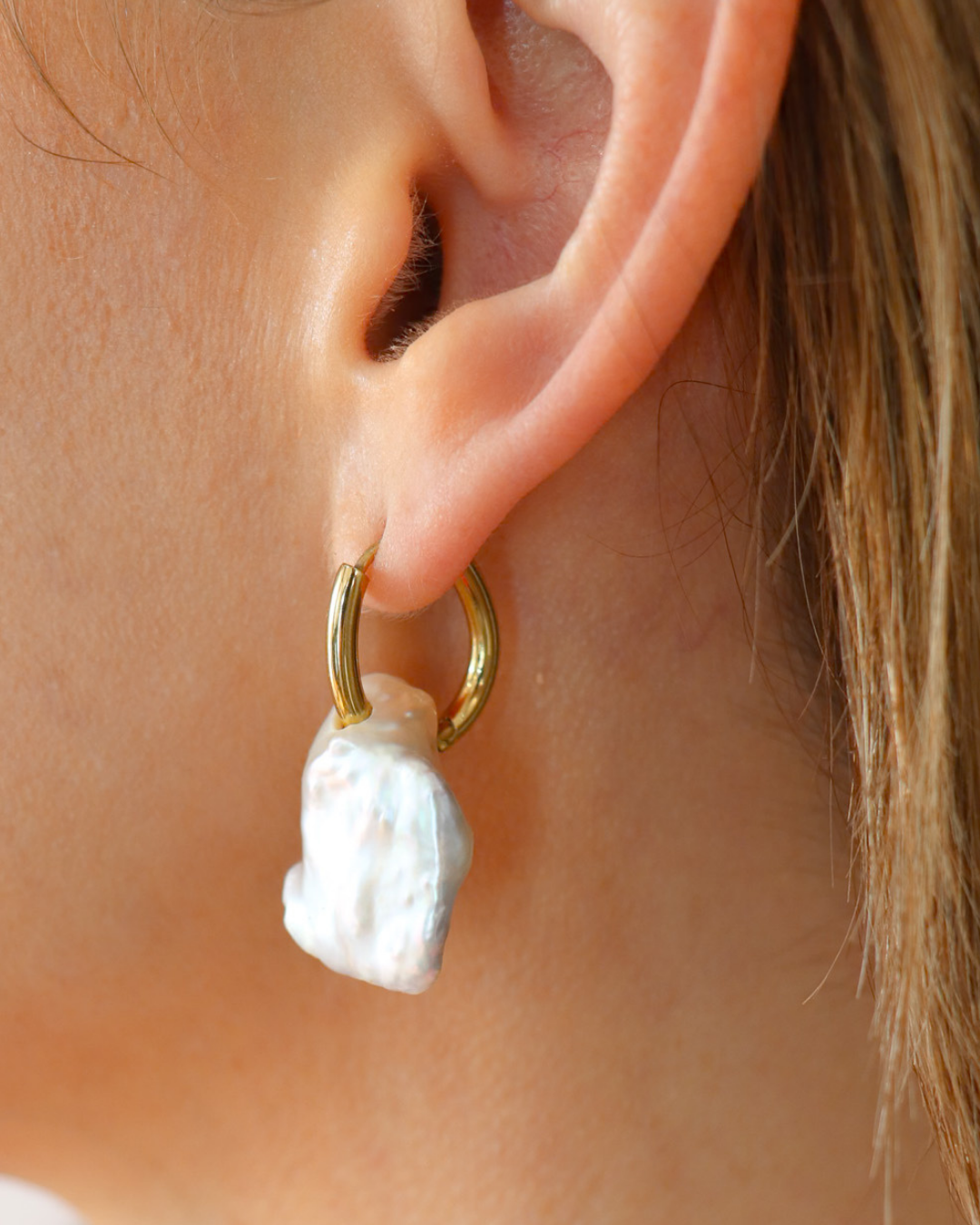 Textured white charm hoop earring with a warm metallic hoop shown worn on the ear