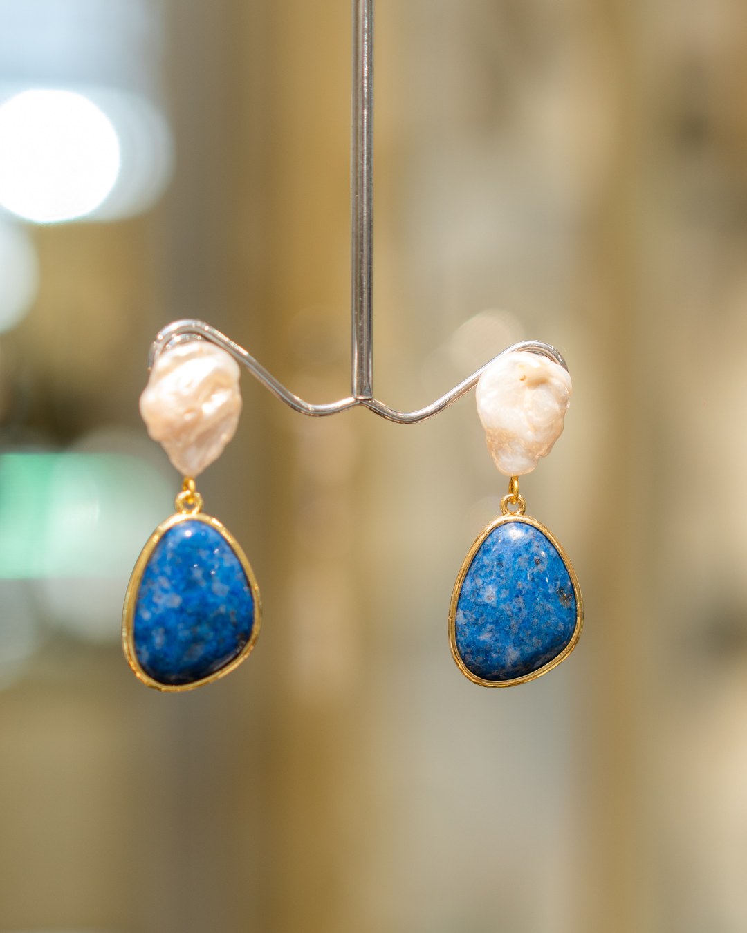 Blue and white drop earrings with rounded blue accents, textured white beads, and warm metallic settings