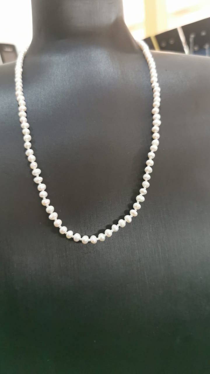 Single strand white pearl necklace on black bust